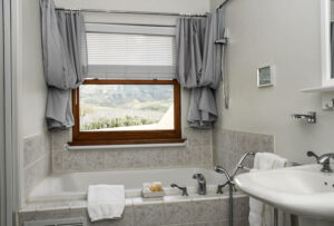 A bathroom with a tub, sink and window.