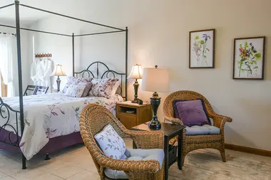 Manzanita Room featuring four poster bed and purple wicker chairs.