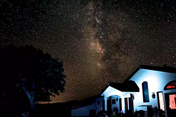 The Milky Way galaxy shining brightly over a house at night.