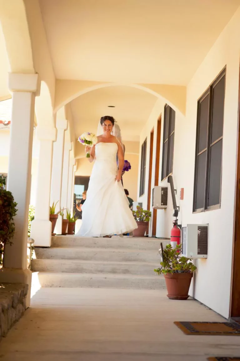 A bride in a white dress walking down a staircase.