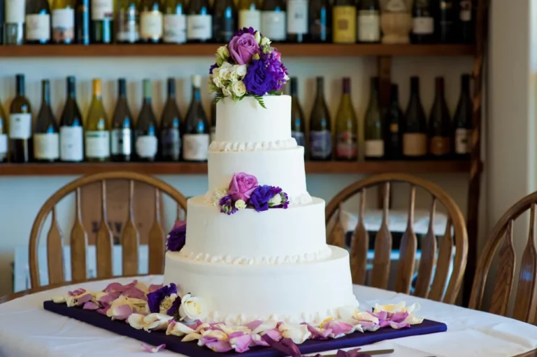 White wedding cake with purple flowers on top, perfect for a wedding celebration.