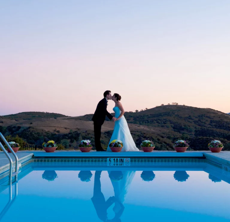 bride and groom kissing by pool.